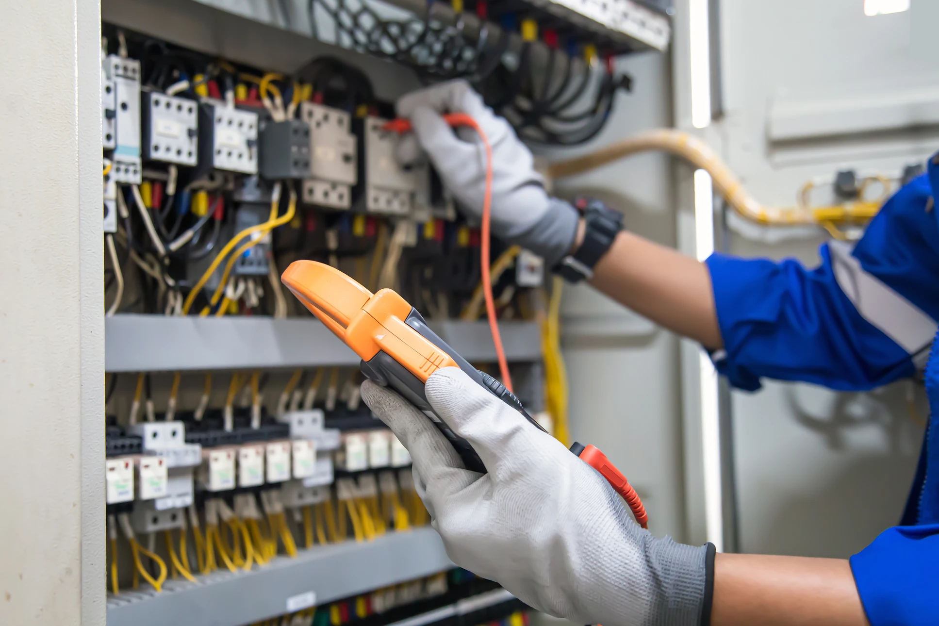 Électricien en combinaison bleue travaillant sur tableau électrique ouvert