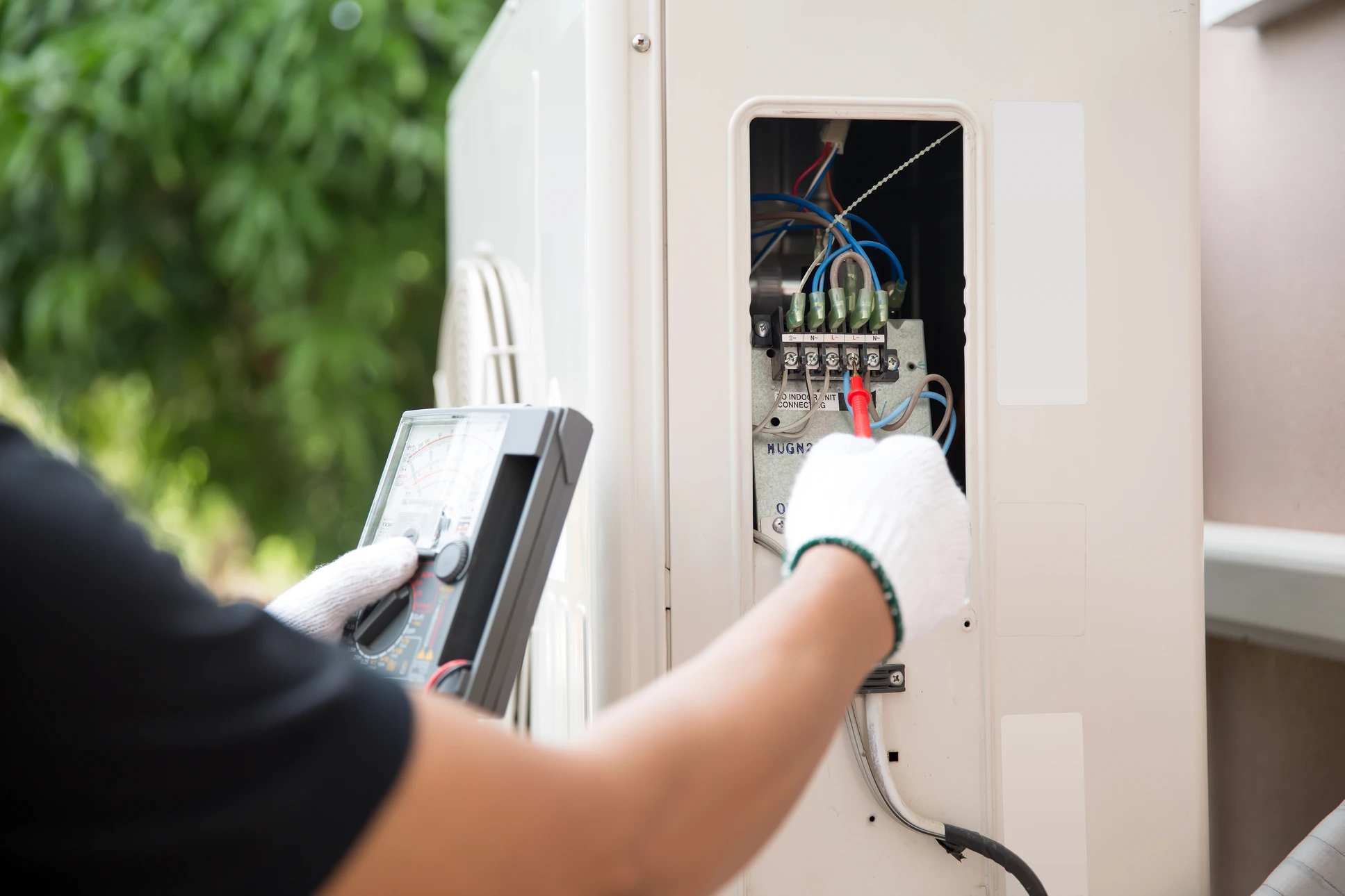 Électricien en combinaison bleue effectuant des mesures électriques dans un tableau de distribution ouvert