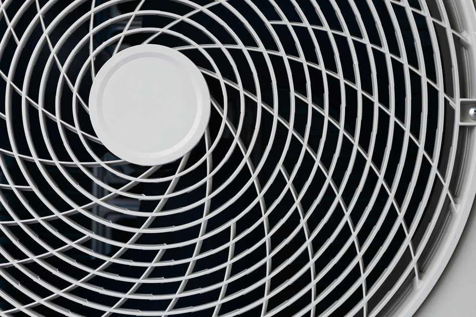 Technicien installant une unité extérieure de climatisation sur façade en briques